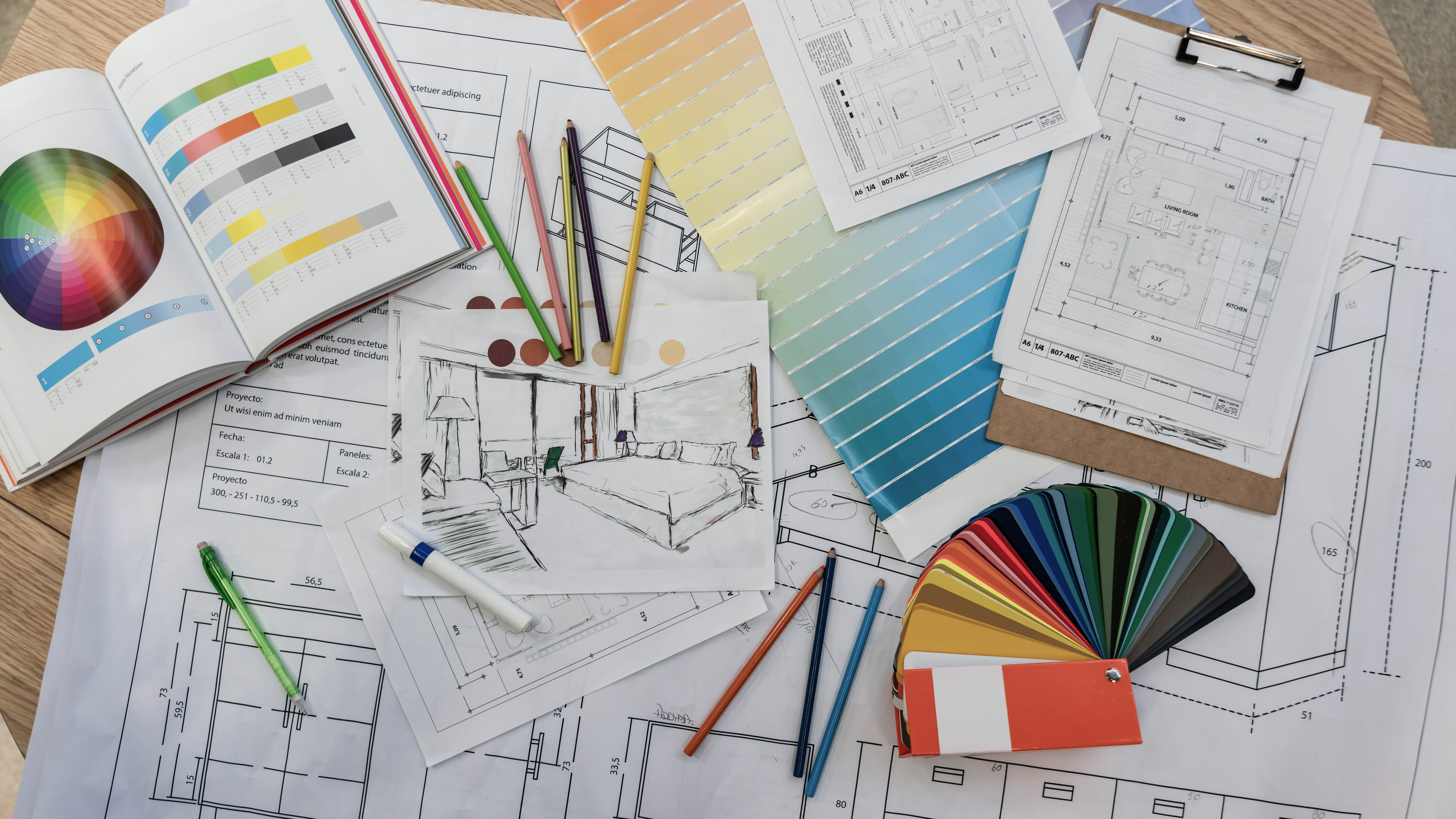 Farben, Skizzen und Pläne für Innenarchitektur auf einem Tisch, umgeben von Stiften und Farbmustern.