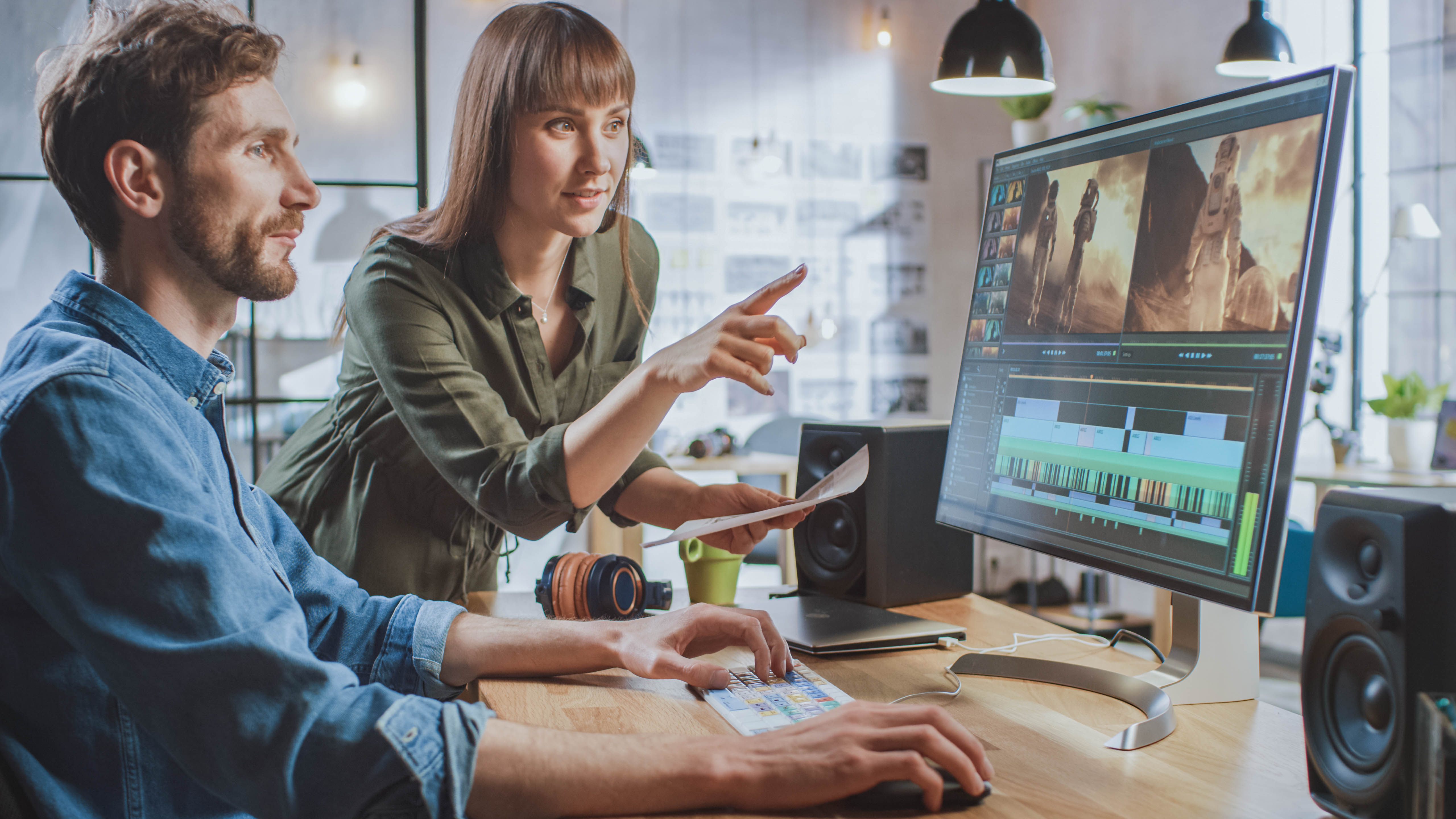 Zwei Personen arbeiten an einem Computer, während sie einen Video-Editing-Prozess besprechen.