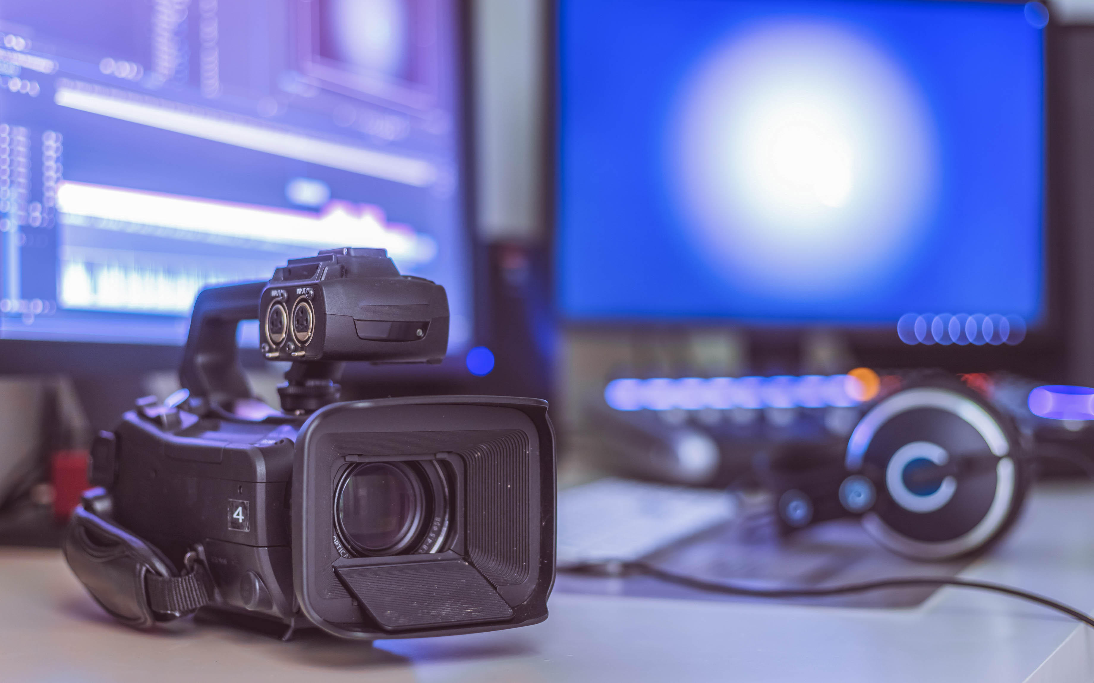 Videokamera im Vordergrund mit zwei Monitoren und Kopfhörern im Hintergrund.