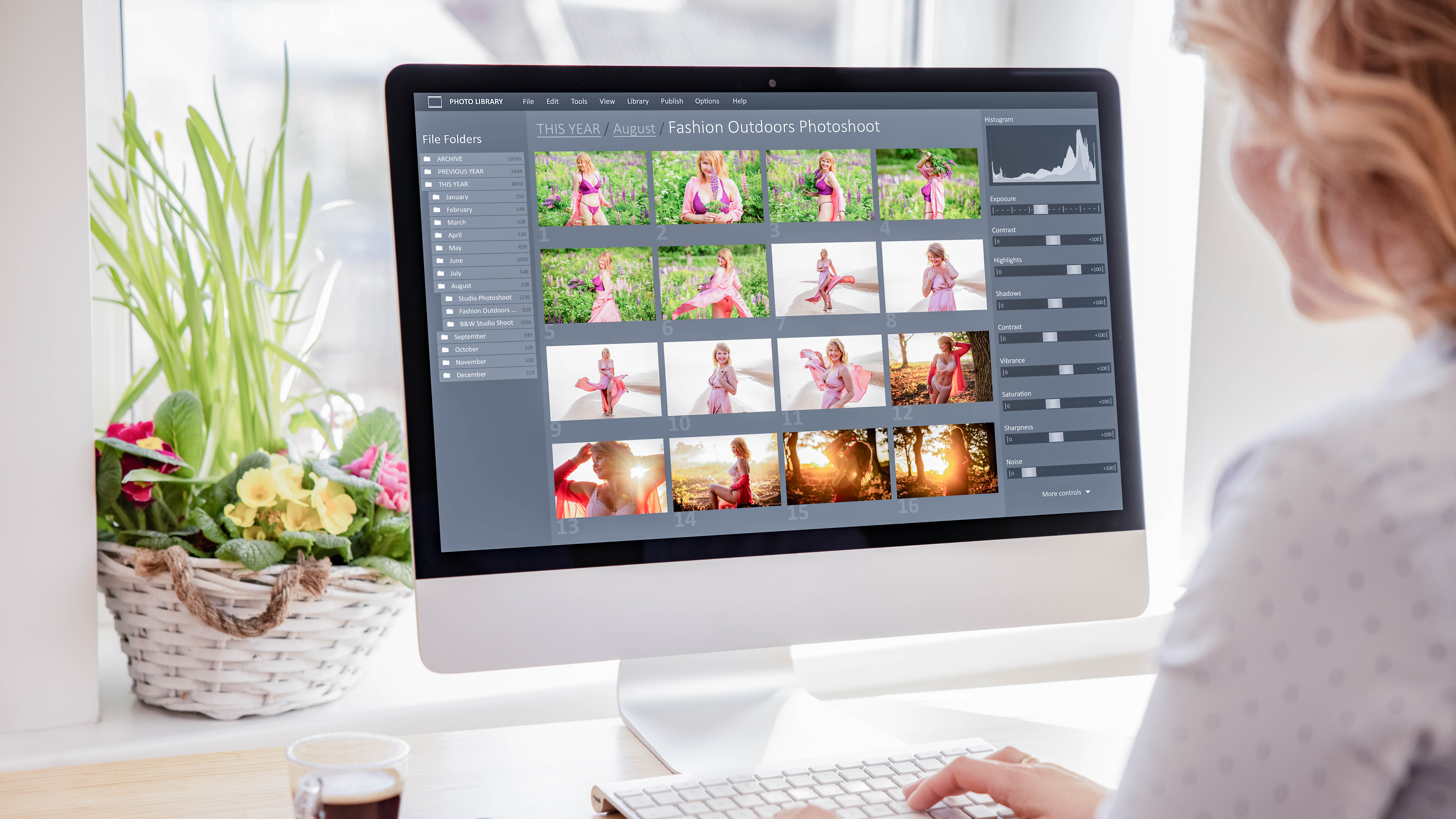 Eine Person sitzt vor einem Computer, auf dem eine Fotobibliothek mit Bildern eines Modeshootings angezeigt wird.