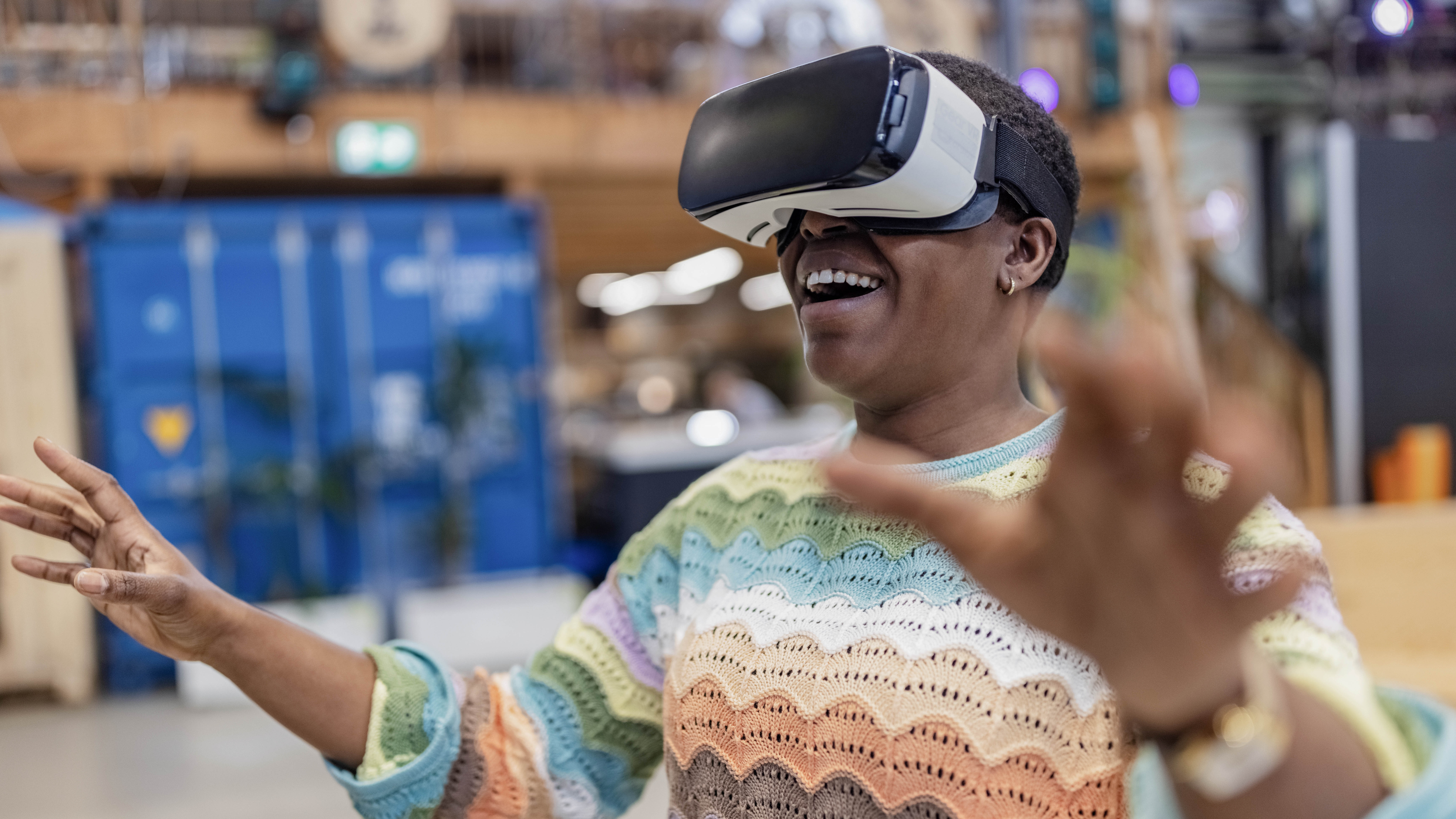Eine Person mit VR-Brille lächelt und bewegt die Hände in einem modernen Raum.