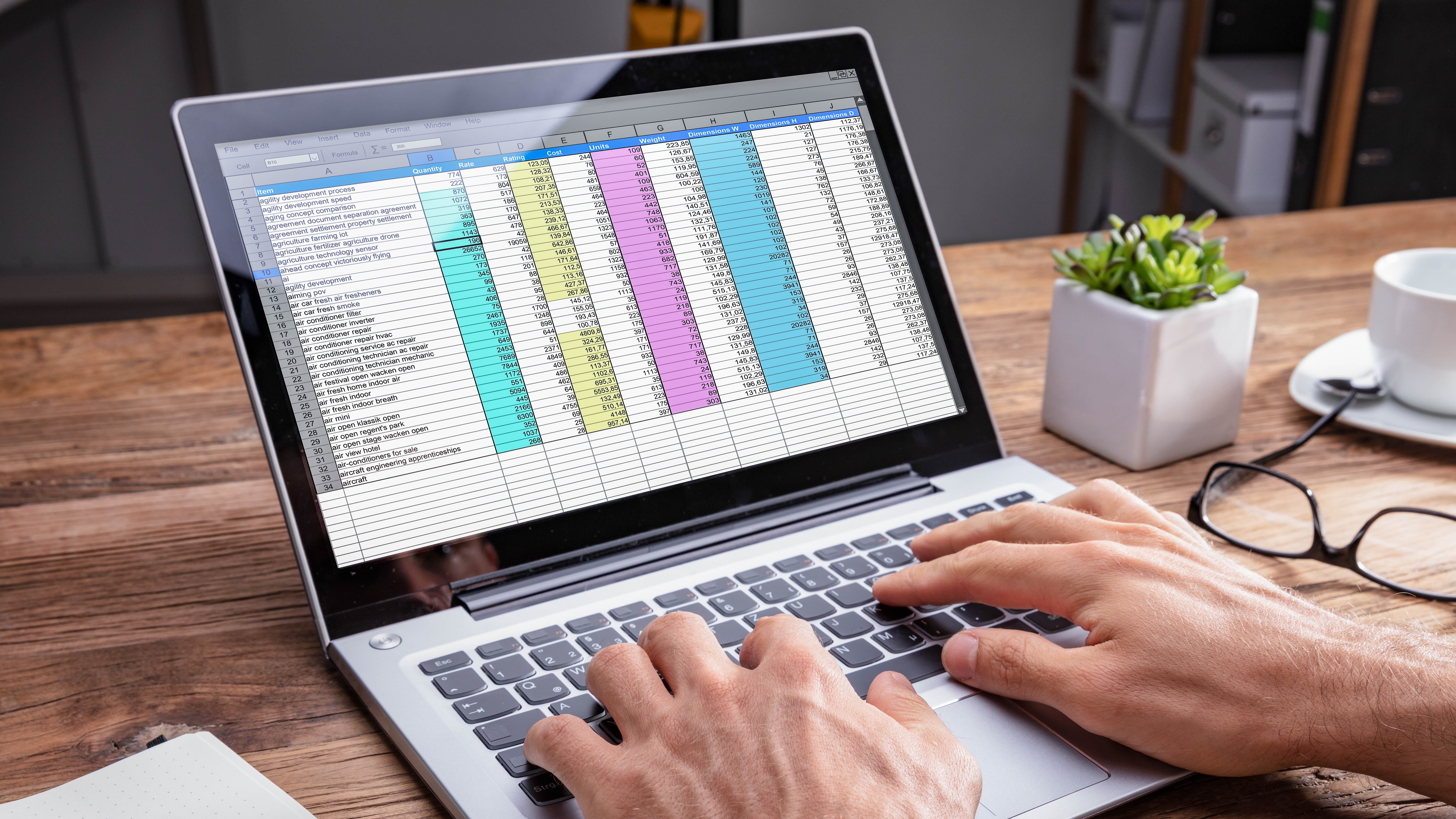Hände tippen auf einer Laptop-Tastatur, während eine Excel-Tabelle auf dem Bildschirm sichtbar ist.