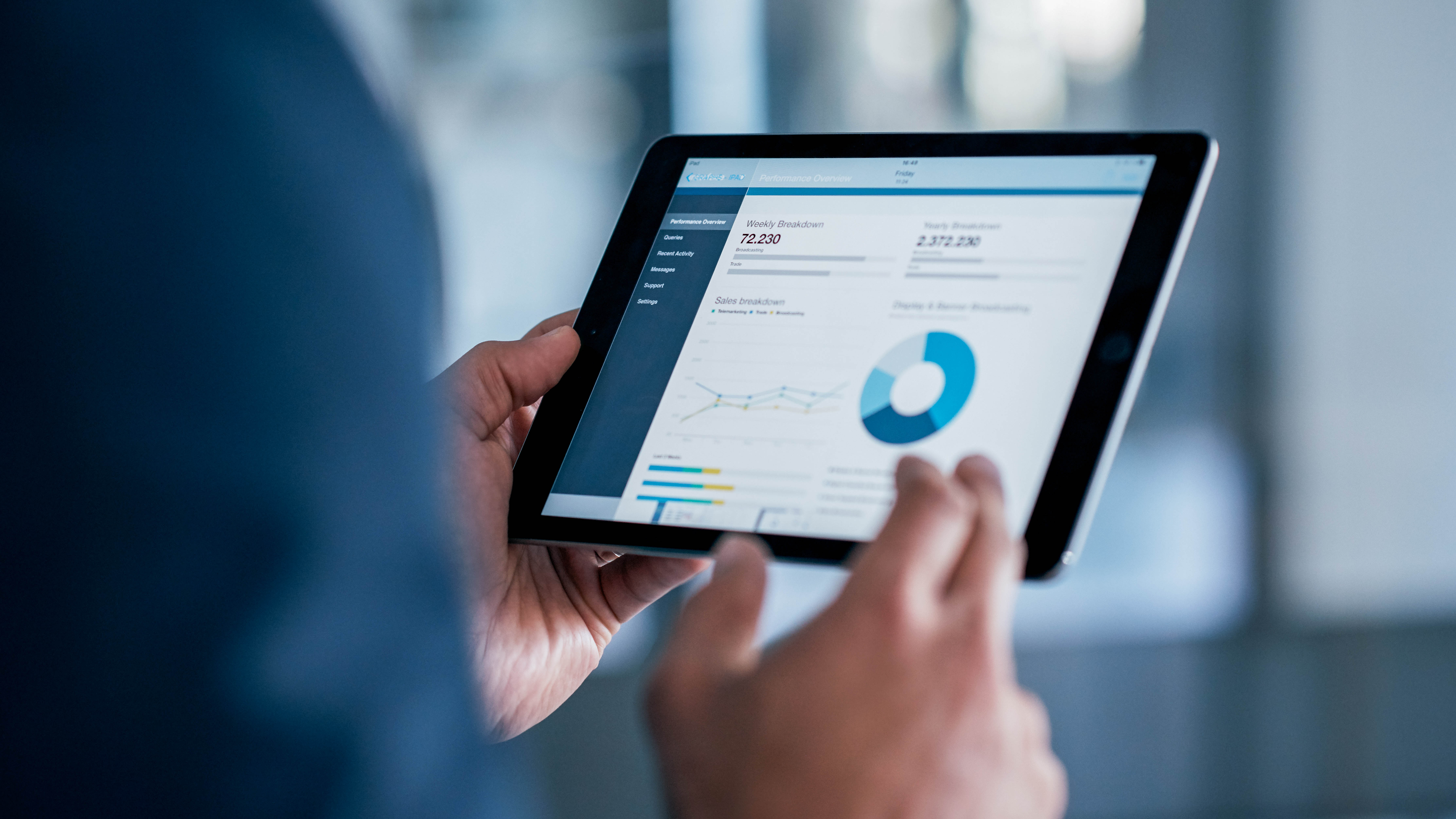 Eine Person hält ein Tablet, auf dem eine grafische Übersicht von Leistungsdaten angezeigt wird.