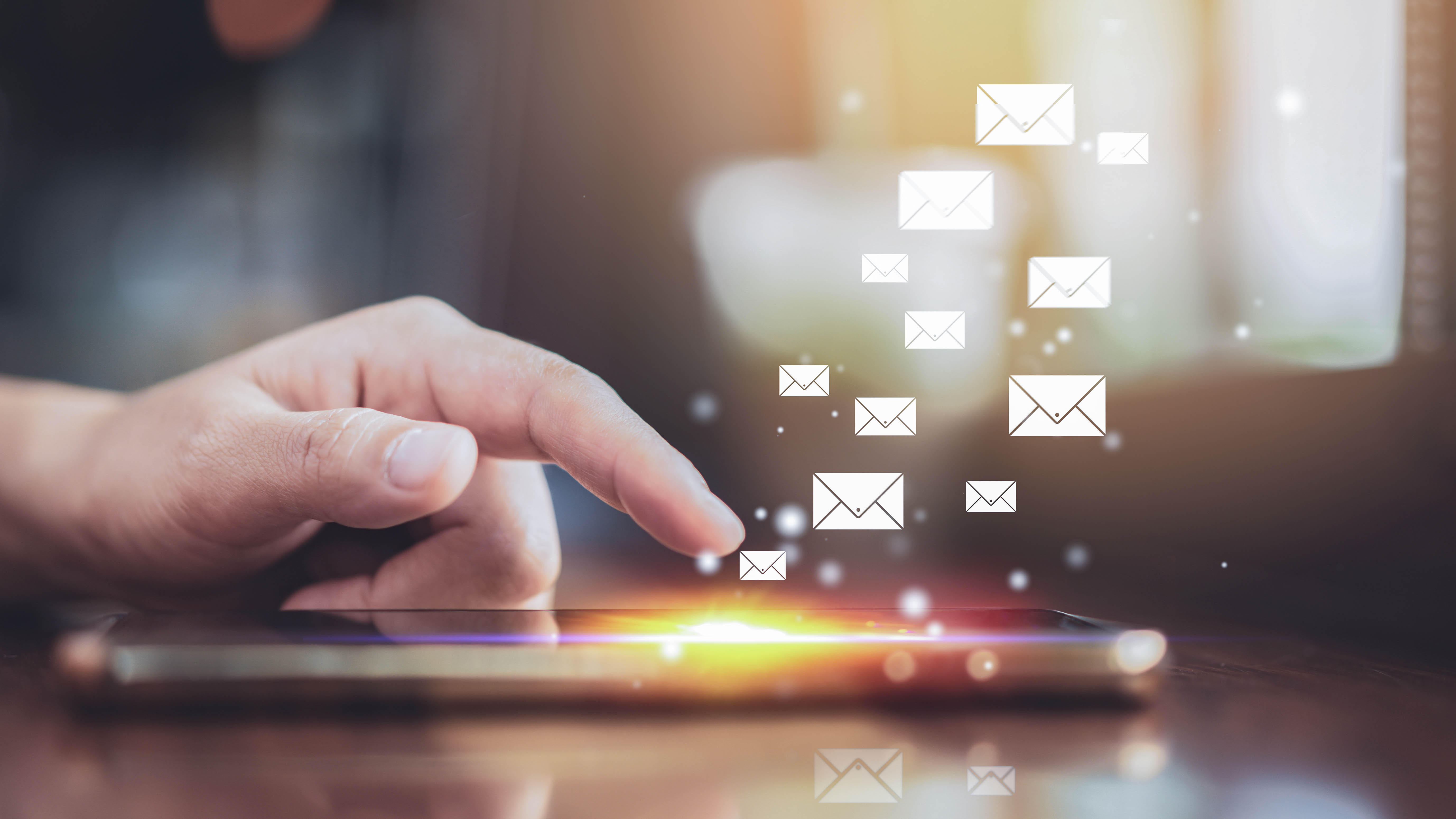 Eine Hand tippt auf einen Smartphone-Bildschirm, während E-Mail-Symbole darüber schweben.