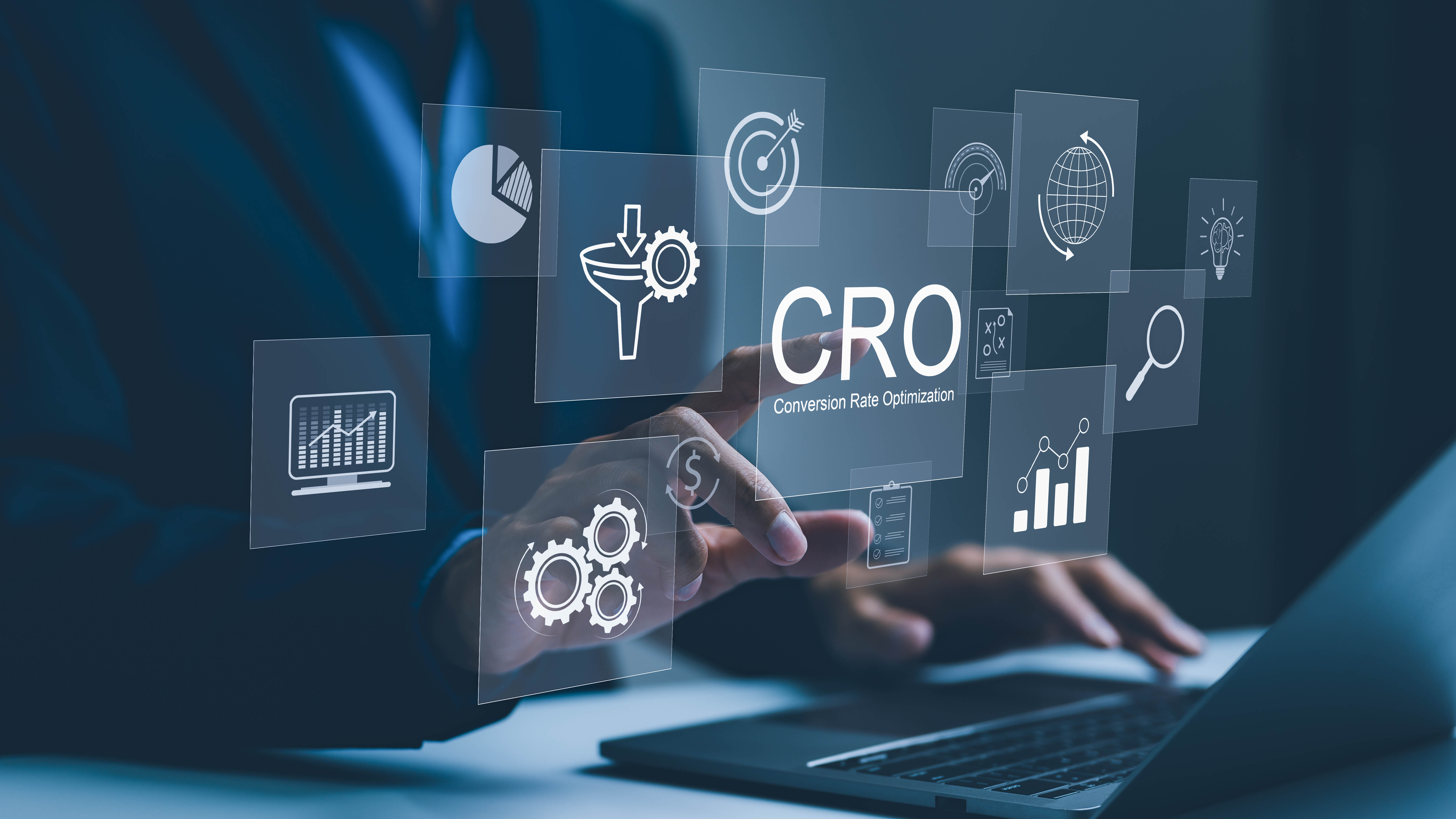 Hand, die auf ein Display mit Symbolen zur Conversion-Rate-Optimierung (CRO) zeigt, vor einem Laptop.