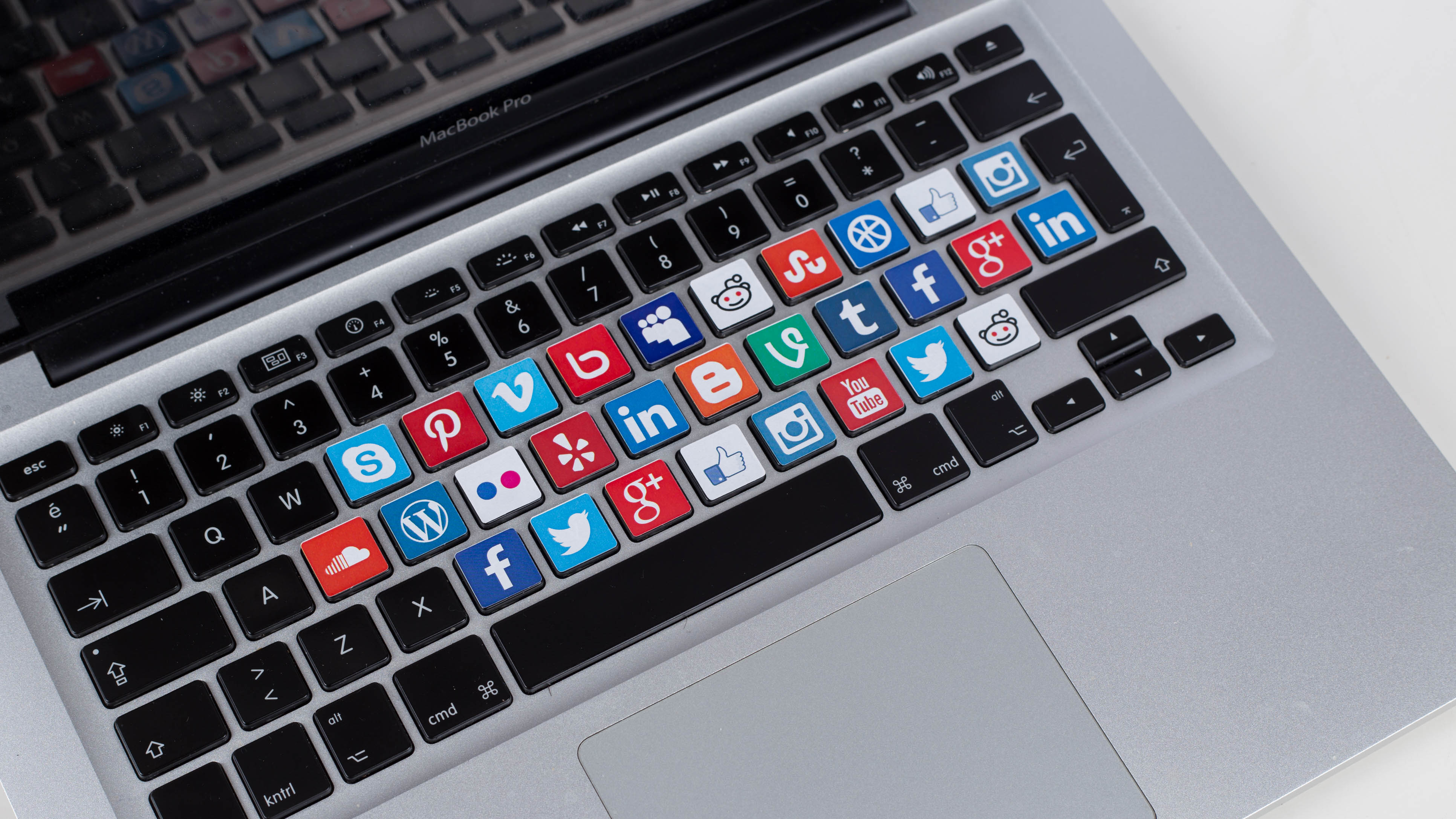 Tastatur eines MacBook Pro mit farbigen Tasten, die verschiedene Social-Media-Icons zeigen.