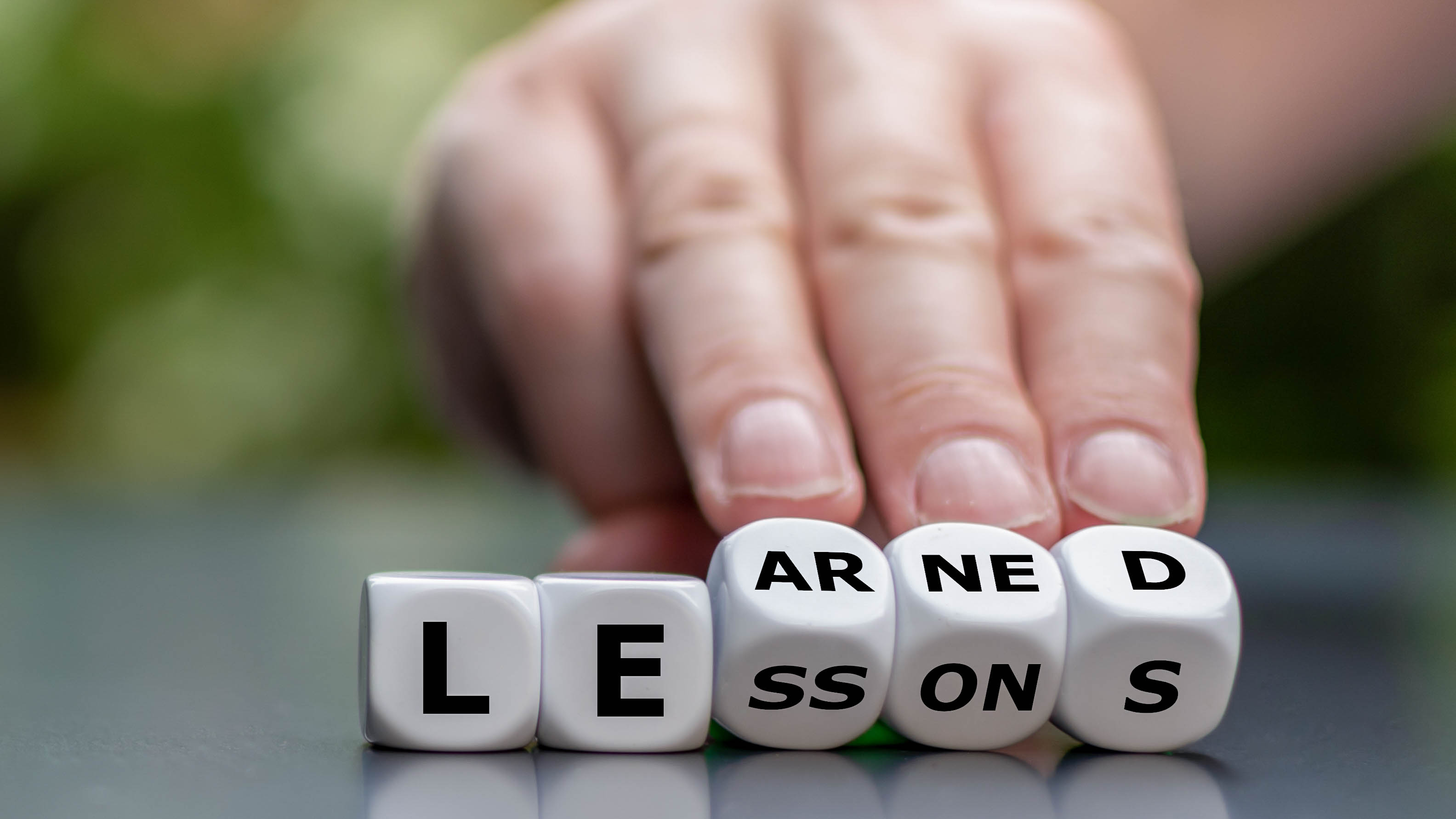 Ein Hand drückt auf Würfel mit den Buchstaben 