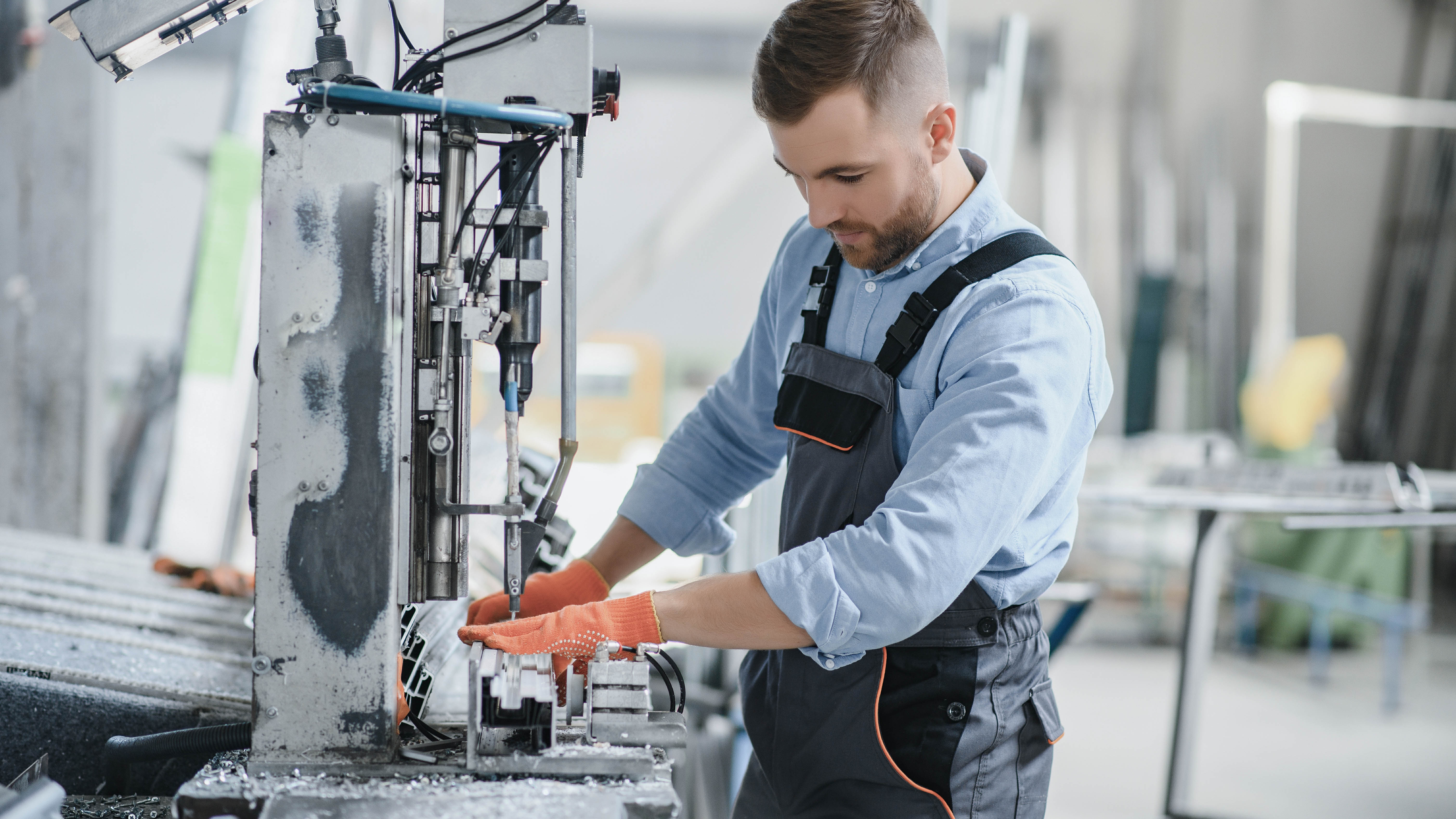 Ein Mann in Arbeitskleidung bedient eine Maschine in einer Werkstatt.