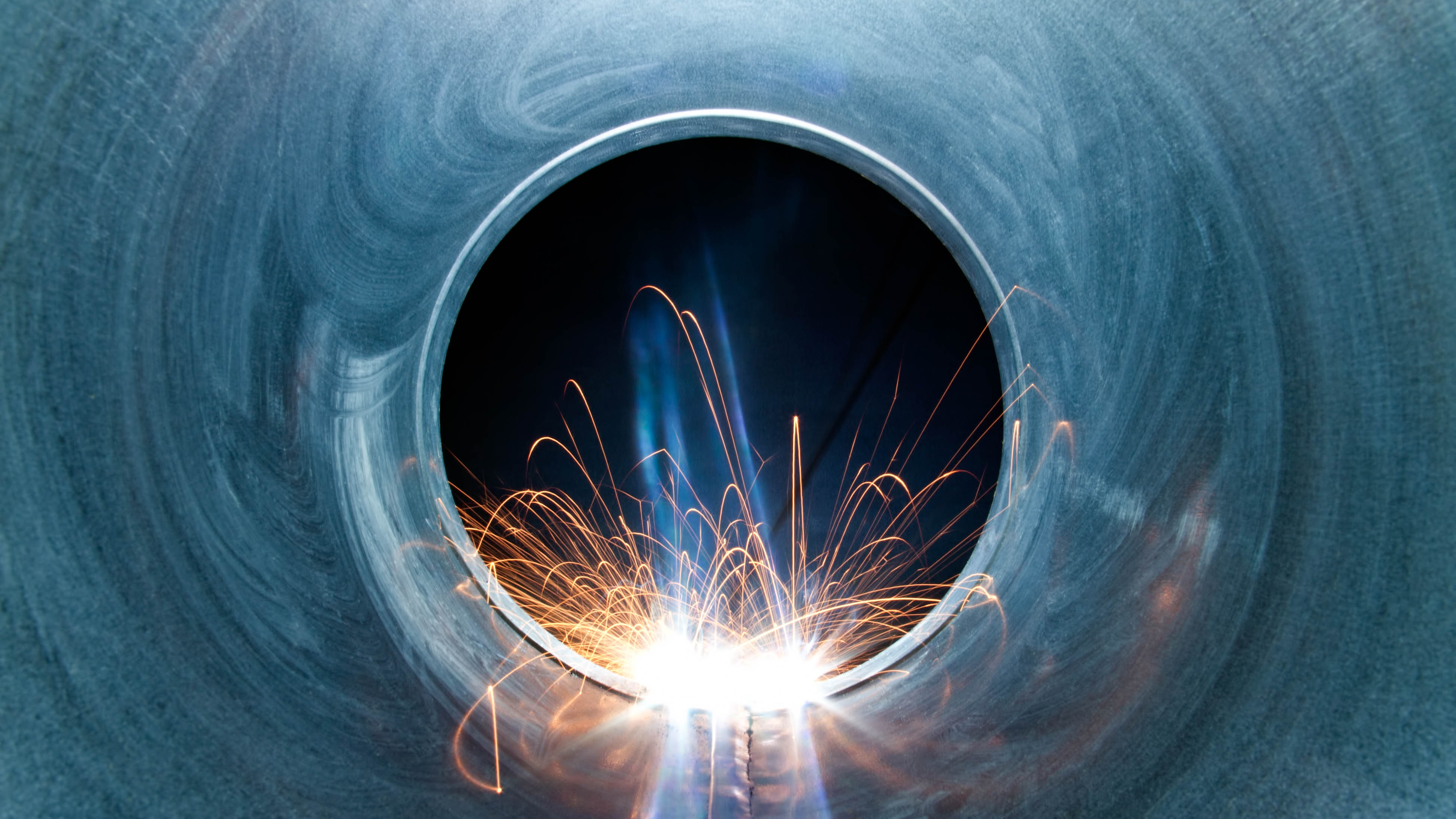 Funken sprühen aus einem runden Metallrohr, das von innen betrachtet wird.