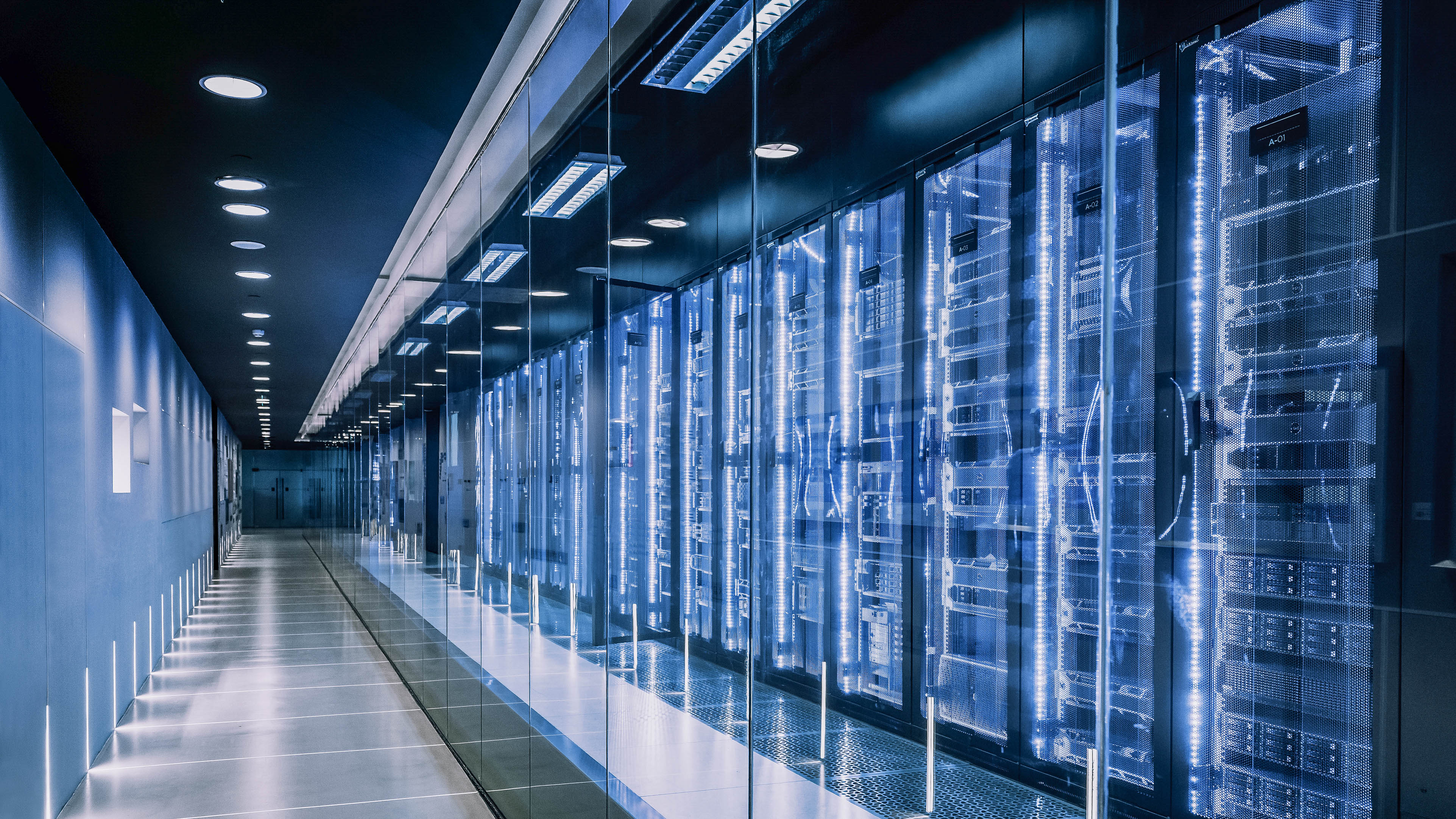 Ein langer, beleuchteter Gang mit Glaswänden und mehreren Server-Racks auf der rechten Seite.