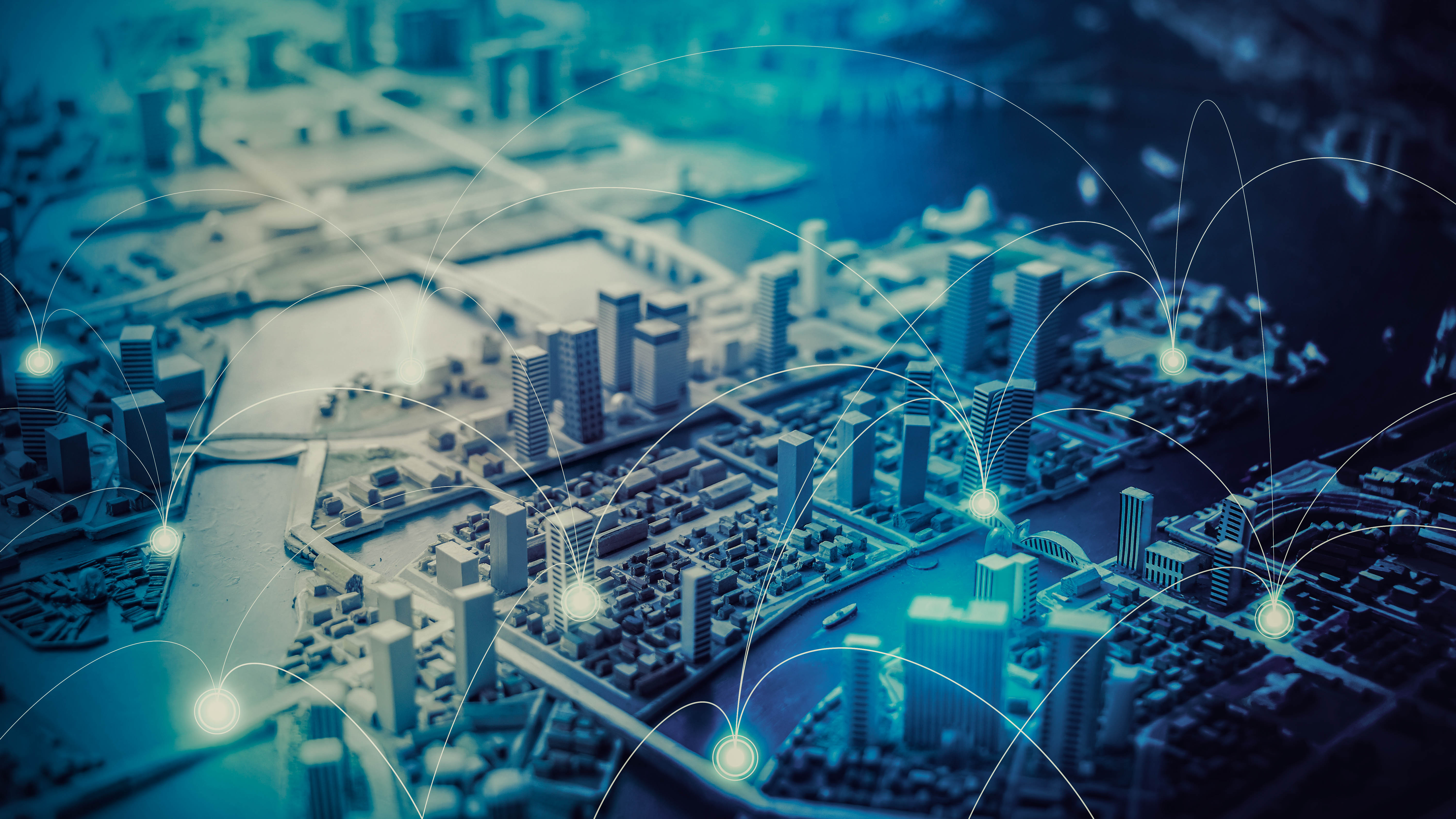 Modell einer Stadt mit Gebäuden und Wasserflächen, verbunden durch digitale Netzwerklinien.
