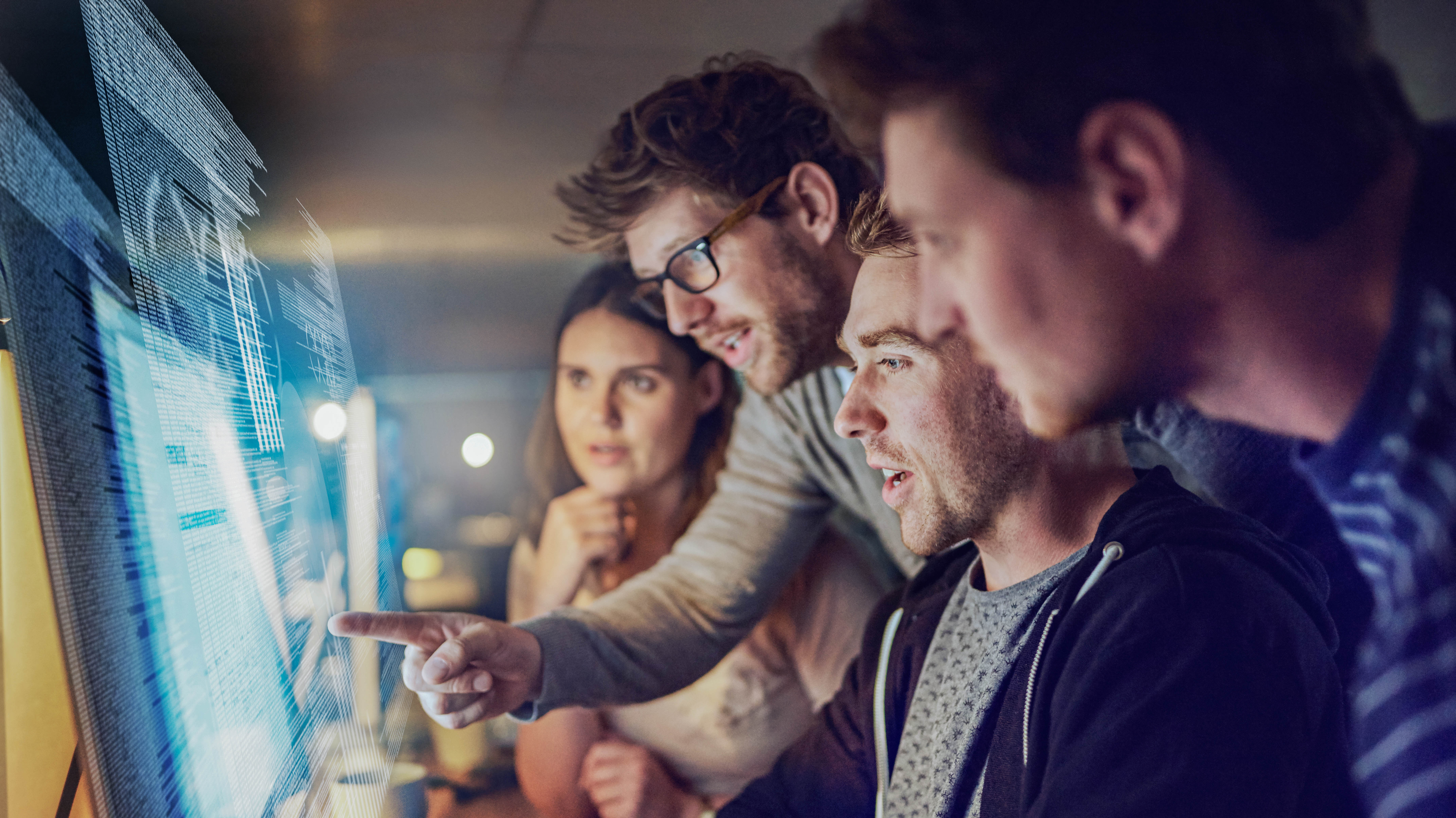 Vier Personen schauen konzentriert auf einen Computerbildschirm und diskutieren.