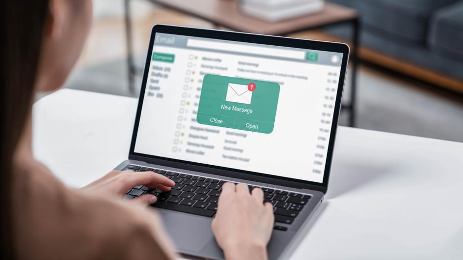 Eine Person tippt auf einer Laptop-Tastatur, während ein neues Nachrichtensymbol auf dem Bildschirm angezeigt wird.
