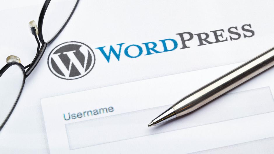 Brille und Kugelschreiber liegen neben einem WordPress-Anmeldeformular mit dem Feld für den Benutzernamen.