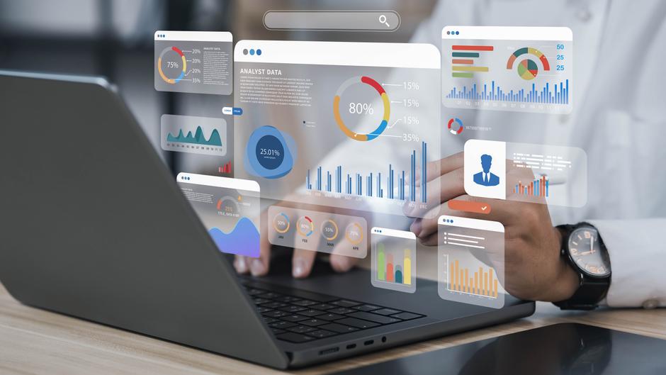 Ein Laptop mit grafischen Datenanalysen und Diagrammen auf dem Bildschirm, während eine Hand tippt.