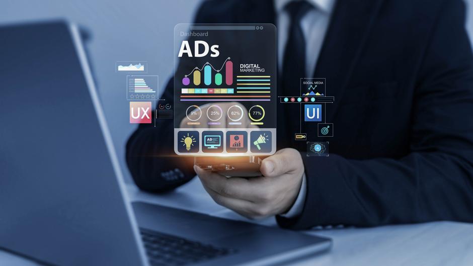 Ein Mann in Anzug hält ein digitales Dashboard mit Grafiken und Symbolen zu digitalem Marketing in der Hand.
