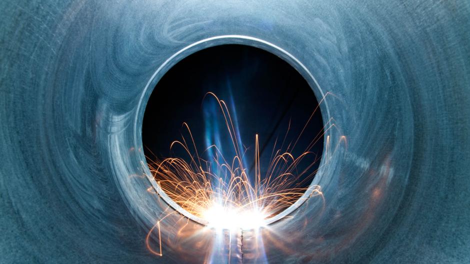 Funken sprühen aus einem runden Metallrohr, das von innen betrachtet wird.
