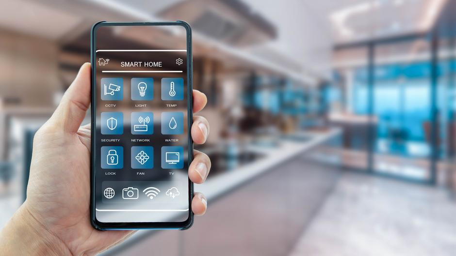 Smartphone in Hand mit einer Benutzeroberfläche für Smart Home-Funktionen wie Licht, Sicherheit und Temperatur.