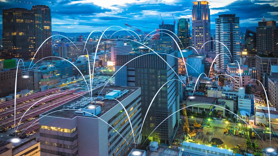 Städtische Skyline bei Dämmerung mit Netzwerkverbindungen zwischen Gebäuden und Straßen.