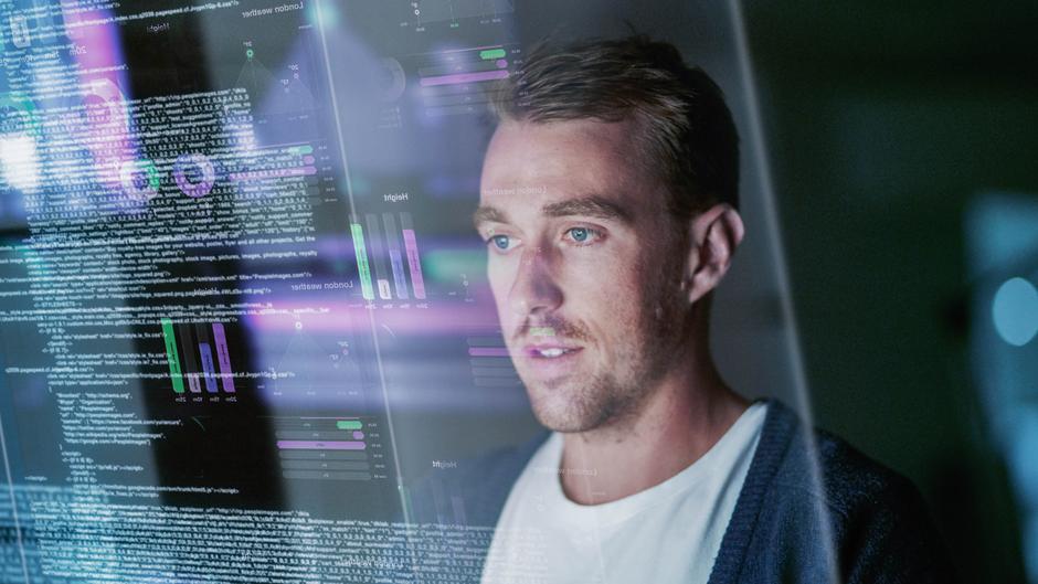Ein Mann betrachtet Datenvisualisierungen und Programmiercode auf einem Bildschirm.