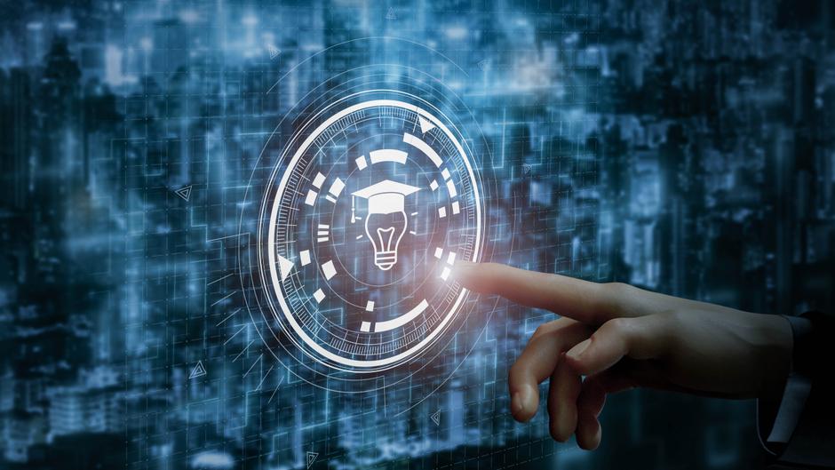 Hand tippt auf ein digitales Symbol mit einer Glühbirne und einem Abschluss-Hut vor einem futuristischen Hintergrund.