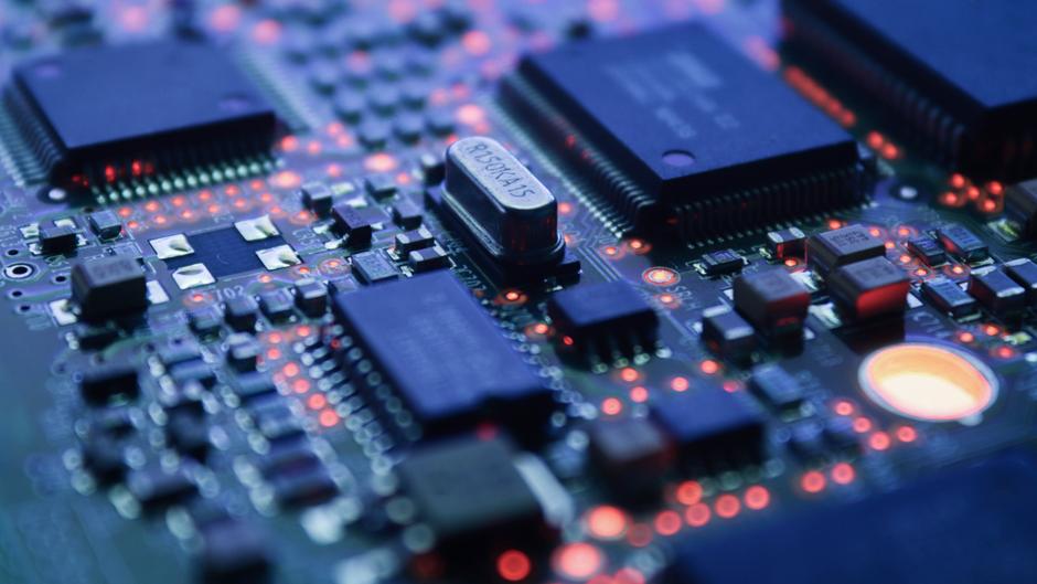 Nahaufnahme einer Leiterplatte mit verschiedenen Chips und leuchtenden LEDs.