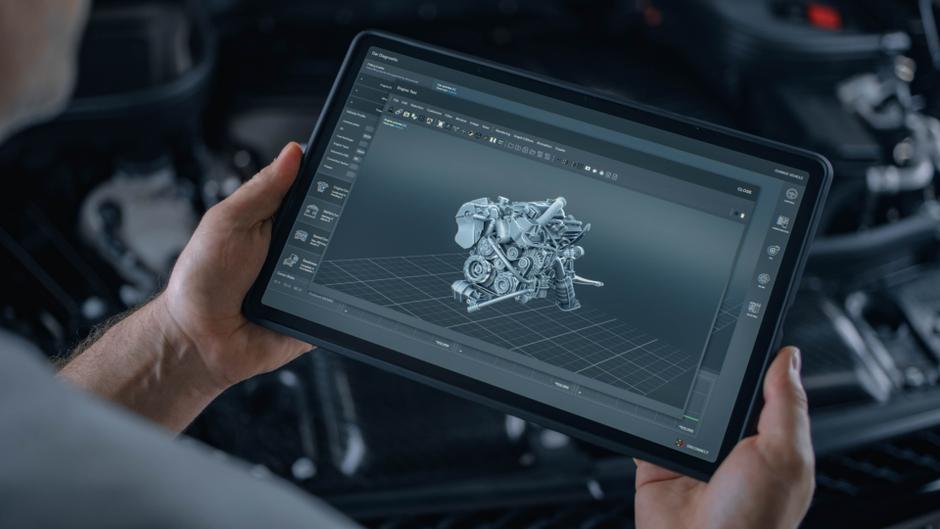 Eine Person hält ein Tablet, auf dem ein 3D-Modell eines Automotors angezeigt wird.