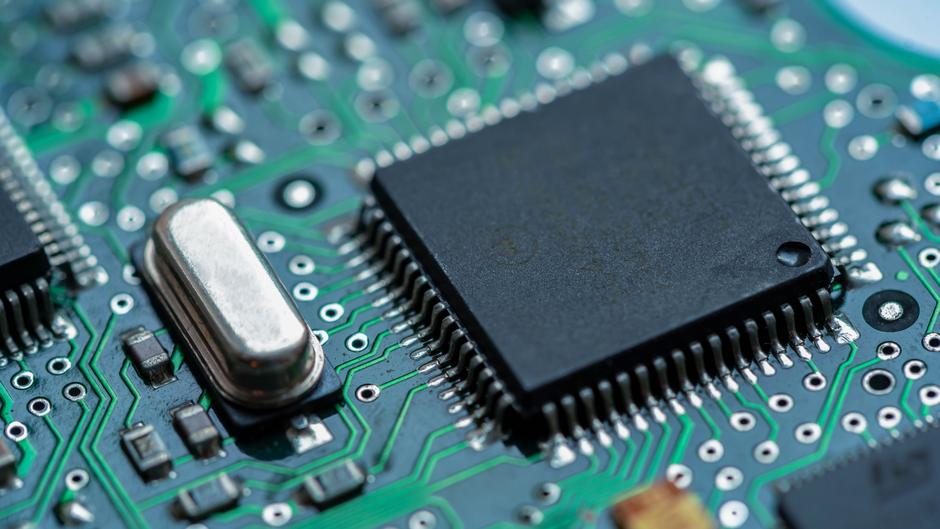 Detailaufnahme einer Leiterplatte mit einem Mikrochip und weiteren elektronischen Bauteilen.
